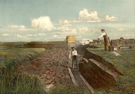 Men extracting peat, the manual work of cutting peat with tools such as shovels. A worker stands on