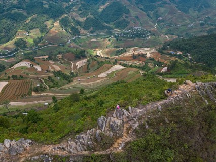 Aerial view of a woman with a pink rucksack sitting on The Dinosaur Backbone (S?ng Lung Kh?ng