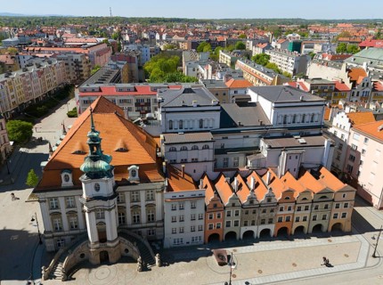 A square in the city center surrounded by pastel-colored historic buildings and a church tower,