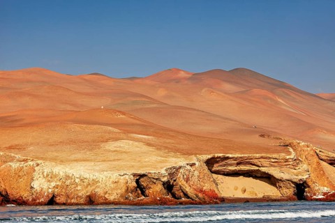 Sandy desert landscape with rocky coast under clear blue sky, The rocky coast with desert near