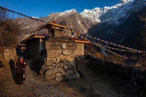 Young woman next to a small Buddhist monastery with manistones in the evening light, Nepalese,