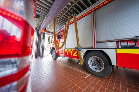 Interior view of a fire department garage with red fire engines and hoses on the ceiling, Gechingen