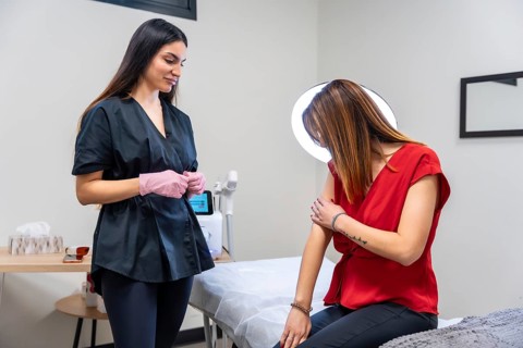 Medical specialist in a clinic explaining a tattoo removal procedure or aesthetic treatment to a