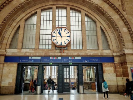 Entrance area of a train station with clock and people passing through, train station, Leipzig main