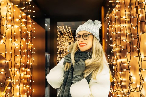 Young woman in winter clothing in a corridor with garlands. A woman wearing a gray knit hat,