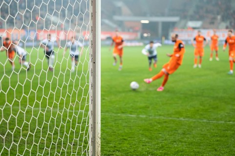 Detail of goal's post with net and football player during penalty kick in the background in Lubin,