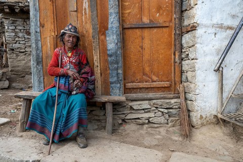 Elderly Nepalese woman from a Hindu ethnic group wearing traditional clothing on a wooden bench in