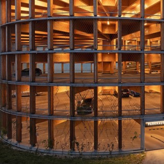 03.05.2026: Illuminated modern timber parking garage (Parkhaus am Bahnhof) with a curved wooden