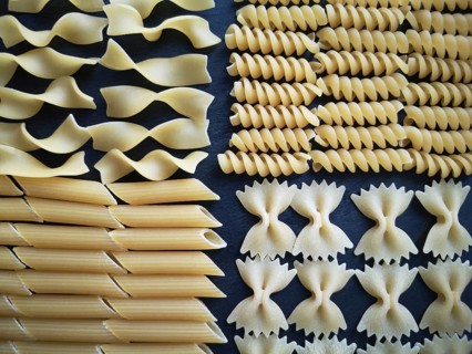 The texture of four types of pasta: tagliatelle, farfalle, penne and fusilli.Close-up. Top view.