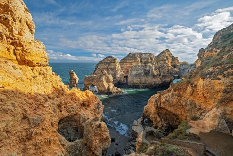 The ocean cove at Ponte da Piedade, Lagos, Algarve, Portugal, is bordered by golden cliffs and sea