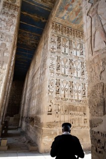 A police guard beside reliefs and hieroglyphs inside Medinat Habu, the ancient Egyptian Mortuary
