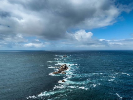 Aerial view of the wild foaming sea at Pointe du Raz with the offshore Phare de la Vieille