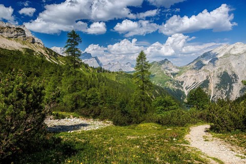 Distant view with rocky mountain trail in the Kawendel Mountains with lush green meadows, Kawendel,
