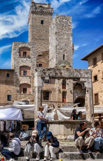 Tourists around the market square with old fountain and other sights in San Gimignano, Tuscany,