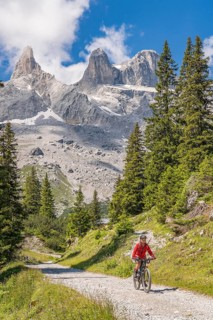 Woman riding her electric mountain bike up to the Lindau Hut below the famous summits of Drusenfluh
