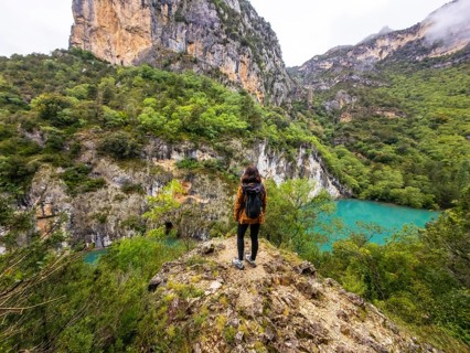 Woman standing on a rocky outcrop overlooking the turquoise waters of the cinca river, surrounded