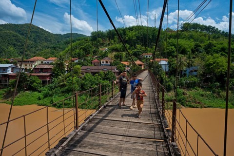 Children on a footbridge over the Nam Phak River which flows into the dammed Nam Ou River in the