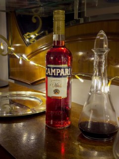 Campari bottle with carafe on wooden counter, evening mood