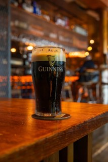 A glass of Guinness stands on a wooden table in a cozy bar setting, Nightlife, Dublin, Ireland