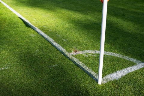 Empty corner kick arc and flag pole on a sunny professional soccer pitch in Glogow, Poland
