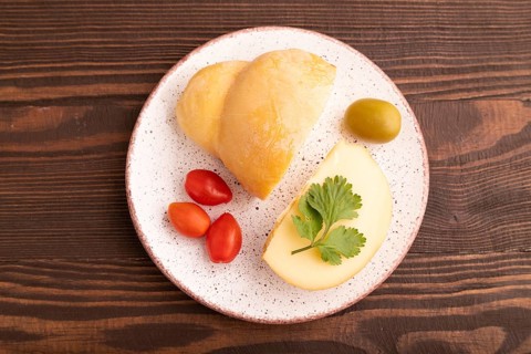 Smoked Mozzarella cheese, with tomatoes and olives on brown wooden background, top view, flat lay,