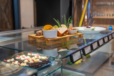 Colourful selection of baked goods and sweets presented in a glass display case on wooden table,