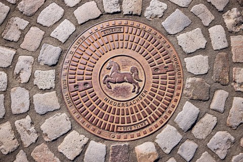 Manhole cover, coat of arms of Lower Saxony, horse, cobblestones, sunny, Bramsche, Osnabrück