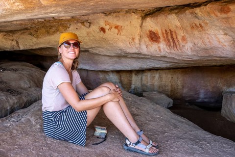 Tourist on a rock with prehistoric animal depictions, ancient rock carving of the San, indigenous