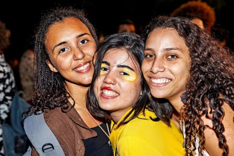 Three close woman smiling happily at the camera with painted faces, visitors to a festival in