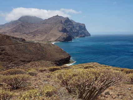Arid landscape with sea views and rocky hills under clear sky, La Aldea de San Nicolas, Gran