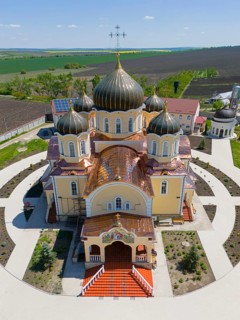 Front view of an orthodox church with symmetrical domes and crosses, rural setting, aerial view,