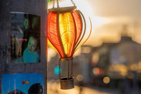A glowing lantern at sunset next to photos on a pole, Dublin, Ireland