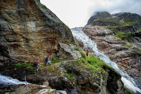 Mountaineers on a hiking trail on a steep rock face, dramatic mountain landscape covered in clouds