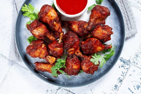 Crispy pieces of fried chicken, on a plate with sauce and herbs, in a modern kitchen environment,