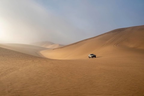 Off-road vehicle between high dunes, sea of dunes, Sandwich Harbour, impressive desert landscape,
