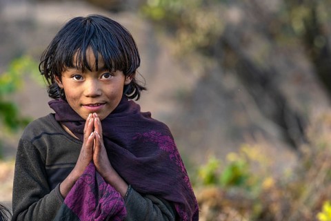 Portrait, young girl folding her hands in greeting Namaste, indigenous people of the Tsumba Tibetan