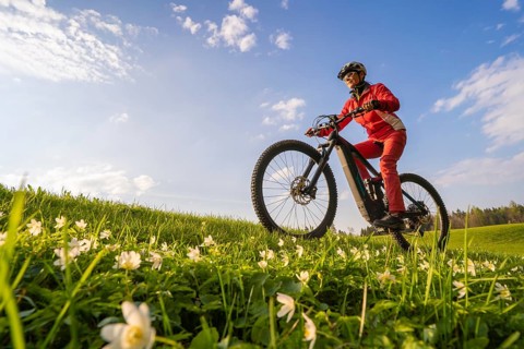 Pretty senior woman riding her electric mountain bike in early springtime in the Allgau mountains