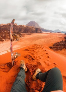 Rider pov Sand boarding from red dune Wadi Rum Jordan, traveler POV with board, desert adventure