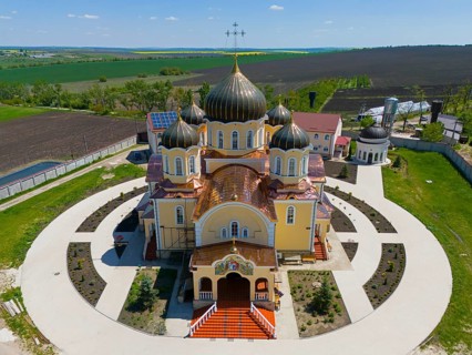 Orthodox church with distinctive domes and crosses nestled in a rural landscape, aerial view,