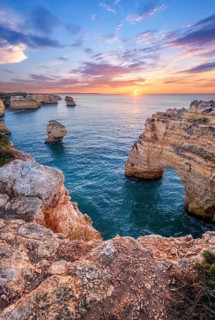 Sunrise at Praia da Marinha beach in Algarve, Portugal, with ocean cliffs, sea stacks and glowing