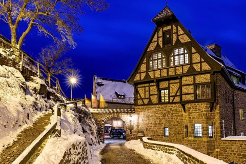 Half-timbered house during the blue hour, illuminated by warm lighting, surrounded by snow and