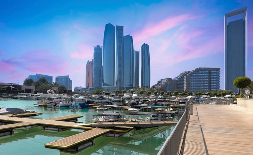 Iconic Abu Dhabi waterfront skyscrapers tower above a bustling marina filled with luxury yachts,