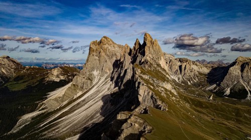 Majestic mountain landscape with dramatic rocks under blue skies and clouds, hiking trails wind