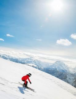 Girl On the Ski. a skier in a bright suit and outfit with long pigtails on her head rides on the