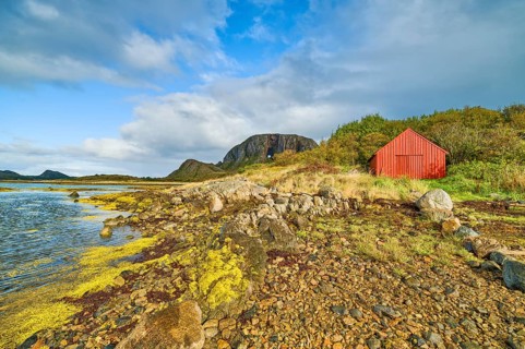 A red house on a rocky coast under a cloudy sky, sea, Torghatten, mountain, Brønnøysund,