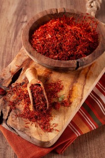 Spice saffron threads, in a wooden bowl, on a wooden table, top view, close-up