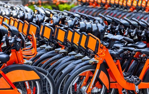 Rows of bright orange rental bikes and nike sharing bicycles parked in the city downtown ready for