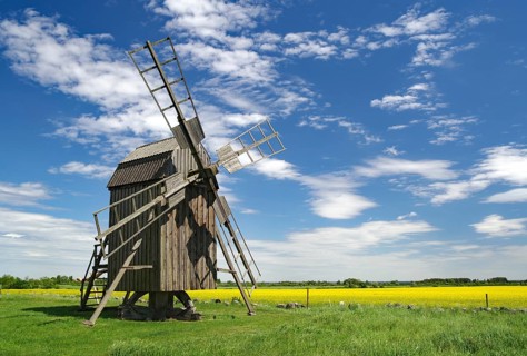 A wooden windmill stands on a green field under a sky with clouds, Lerkaka, Ölandsleden, Öland,