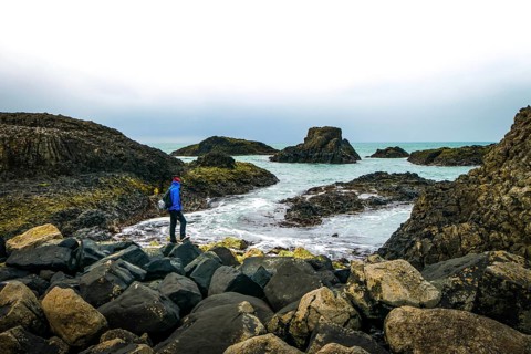 One person is stadig on rocky shore and looking to the sea. Northern Ireland