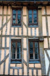 Historic half-timbered façade with distinctive wooden beams and four latticed windows on a